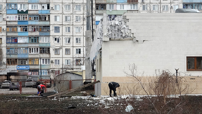 People remove debris near the building damaged by shelling on Saturday in Mariupol, eastern Ukraine, January 25, 2015 (Reuters / Nikolay Ryabchenko)