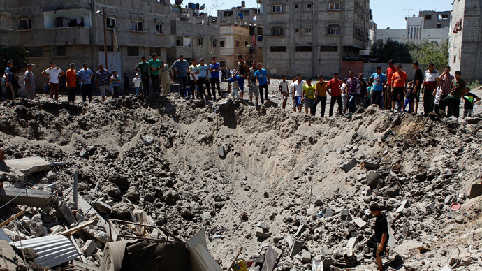 People look at a crater on the ground and damaged buildings, that witnesses said was caused by an Israeli air strike, in the Zeitoun neighbourhood in Gaza City August 8, 2014.(Reuters / Siegfried Modola)