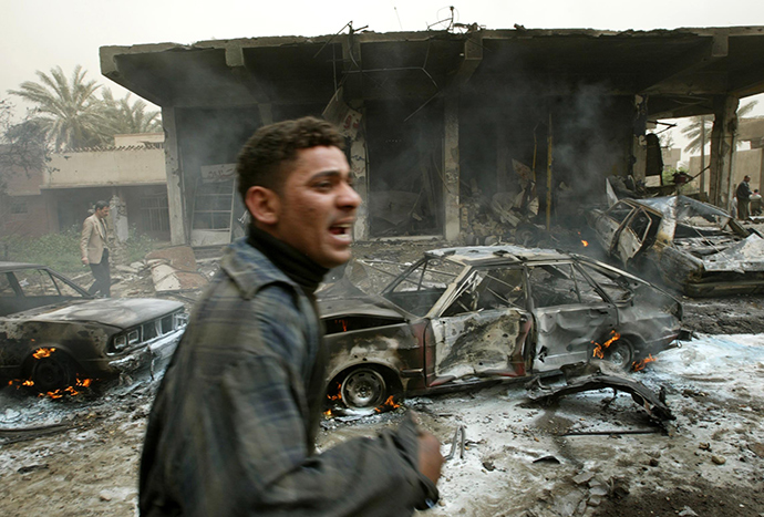 An Iraqi man cries as he runs past a burning car destroyed during an air strike in Baghdad, March 26, 2003 (Reuters)
