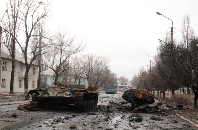 Burnt military machinery in Uglegorsk. Background: a bus column from DPR heading to Debaltsevo for evacuation of local residents from the combat zone. (RIA Novosti)