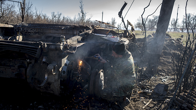 A militiaman of the People's Republic of Lugansk inspects a burnt-out Ukrainian tank in Novosvetlovka. (RIA Novosti / Valeriy Melnikov)