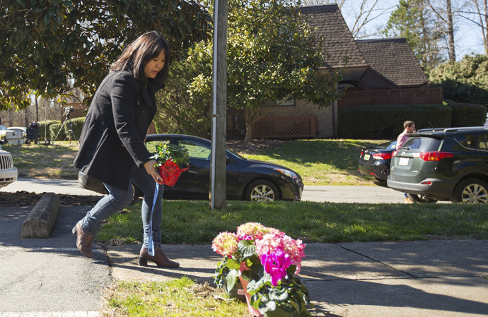 A woman places flowers near a building where three young Muslims were killed on Tuesday, in Chapel Hill, North Carolina February 11, 2015. (Reuters / Chris Keane)
