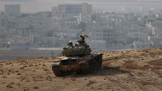 A Turkish soldier sits on top of a tank, with the Syrian town of Kobani in the background, as seen from the southeastern town of Suruc close to the Mursitpinar border crossing on the Turkish-Syrian border (Reuters / Umit Bektas)