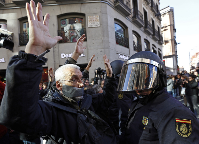 A man, with his mouth taped, faces off with a Spanish riot policeman during a protest against the Spanish government's new anti-protest security law in Madrid December 20, 2014. (Reuters / Sergio Perez)