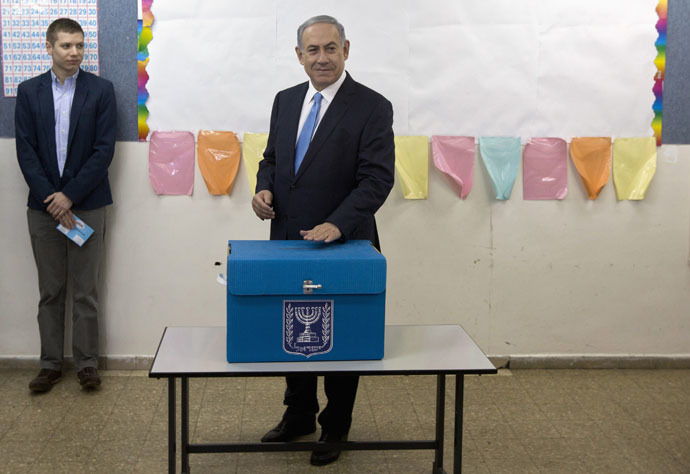 Israel's Prime Minister Benjamin Netanyahu casts his ballot for the parliamentary election as his son Yair stands behind him at a polling station in Jerusalem March 17, 2015. (Reuters/Sebastian Scheiner)