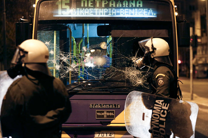 Riot police stand in front of a destroyed trolley bus during clashes with masked youth in Athens March 17, 2015. (Reuters / Alkis Konstantinidis)