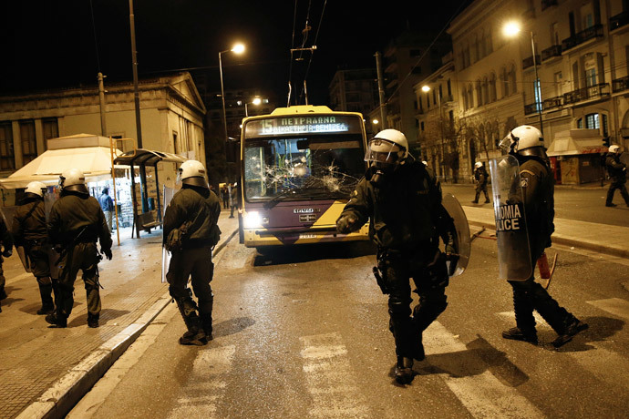 Riot police stand in front of a destroyed trolley bus during clashes with masked youth in Athens March 17, 2015. (Reuters / Alkis Konstantinidis)