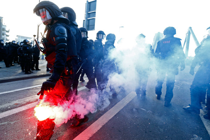 A policeman holds a flare during a protest of members of 'Blockupy' anti-capitalist movement near the European Central Bank (ECB) building before the official opening of its new headquarters in Frankfurt March 18, 2015. (Reuters / Ralph Orlowski)