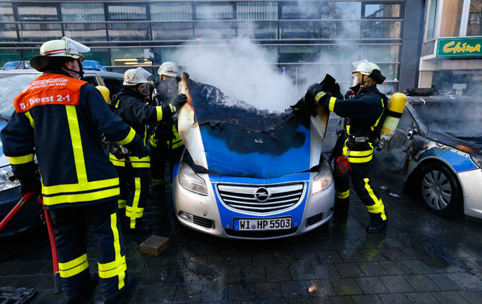 Fireworkers extinguish police vehicles set of fire by anti-capitalist 'Blockupy' protesters near the European Central Bank (ECB) building before the official opening of its new headquarters in Frankfurt March 18, 2015. (Reuters / Ralph Orlowski)
