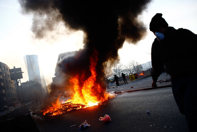 A 'Blockupy' anti-capitalist protester walks near a burning barricade near the European Central Bank (ECB) building before the official opening of its new headquarters in Frankfurt March 18, 2015. (Reuters / Kai Pfaffenbach)