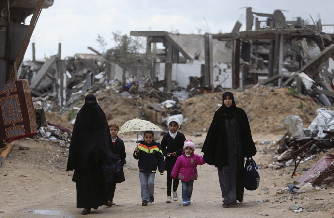 Palestinians walk near the ruins of houses that witnesses said were destroyed or damaged by Israeli shelling during a 50-day war last summer, on a winter day east of Gaza City (Reuters/Ibraheem Abu Mustafa)