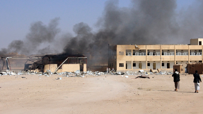 Houthi fighters walk as smoke rises from a military supply post after it was hit by an air strike in Yemen's northwestern city of Saada (Reuters / Naiyf Rahma)