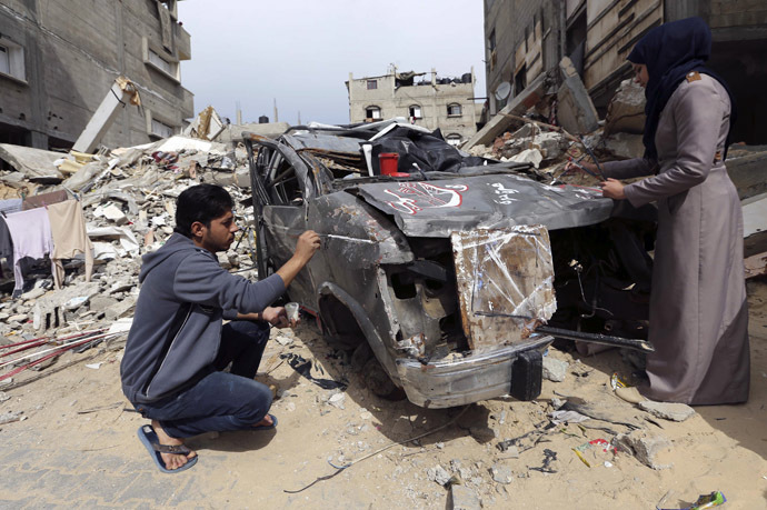 Palestinian artists paint on the remains of car that witnesses said was destroyed by Israeli shelling during a 50-day war last summer, in Rafah in the southern Gaza Strip February 24, 2015. (Reuters/Ibraheem Abu Mustafa)