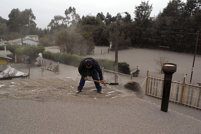 A man cleans the roof of his house at Ensenada town which is covered with ashes from Calbuco volcano near Puerto Varas city, April 23, 2015 (Reuters / Ivan Alvarado)