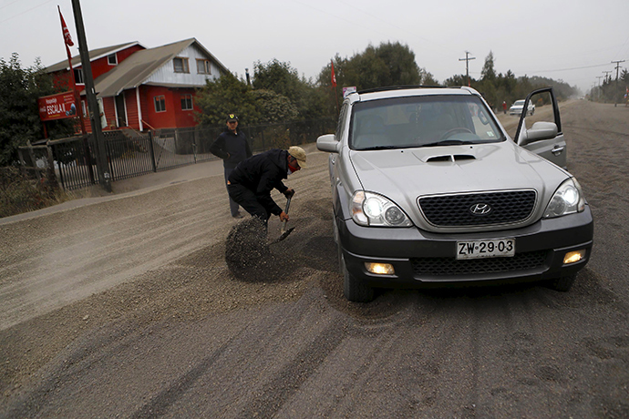 A man removes ash under his truck at Ensenada town which is covered with ashes from Calbuco volcano near Puerto Varas city, April 23, 2015 (Reuters / Ivan Alvarado)