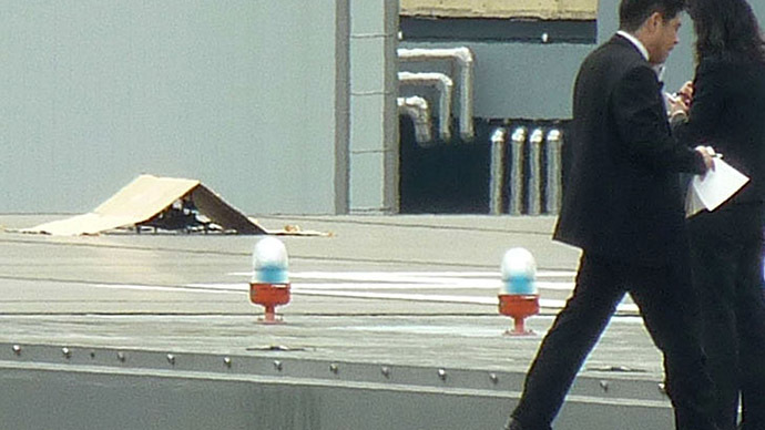 Police and security officers investigate near an unidentified drone (covered under a cardboard) which was found on the rooftop of Prime Minister Shinzo Abe's official residence in Tokyo, in this photo taken by Kyodo April 22, 2015. (Reuters/Kyodo)