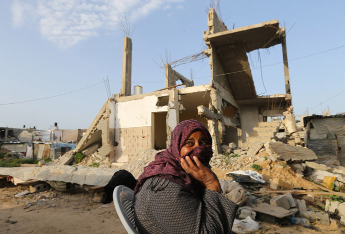 A Palestinian woman sits near her house, that witnesses said was destroyed by Israeli shelling during a 50-day war last summer, in Khan Younis in the southern Gaza Strip, March 10, 2015. (Reuters/Ibraheem Abu Mustafa)