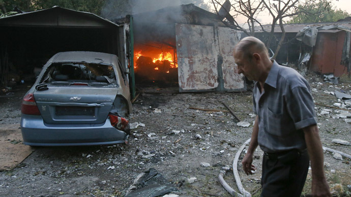 ARCIVE PHOTO: A man walks past a garage set ablaze by what locals say was shelling by Ukrainian forces in Donetsk, September 4, 2014 (Reuters / Maxim Shemetov)