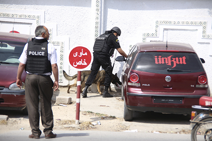 A Tunisian anti-terrorism brigade officer lead his dog outside the Bouchoucha military base after a shooting in Tunis, Tunisia May 25, 2015 (Reuters / Zoubeir Souissi)