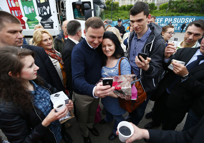 Andrzej Duda (centre L), presidential candidate of the Law and Justice Party (PiS), poses for a picture with passerbys outside a subway station in central Warsaw, Poland May 25, 2015. (Reuters/Pawel Kopczynski)