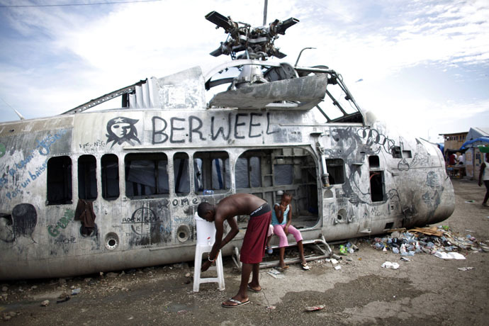 An earthquake survivor washes his hands in a bucket, donated by Haiti's Red Cross to control infections, near a damaged helicopter in a provisional camp in downtown Port-au-Prince October 30, 2010. (Reuters/Eduardo Munoz)