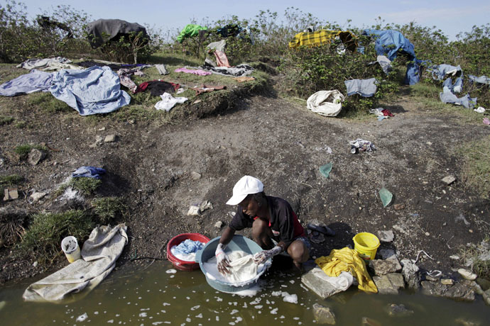 A woman washes her clothes in a pond close to Cite Soleil, in Port-au-Prince, March 21, 2015. (Reuters/Andres Martinez Casares)