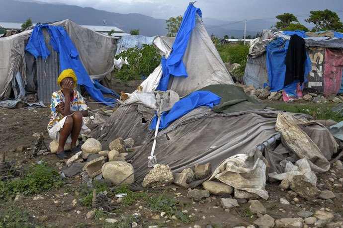 A Haitian woman living in a tent camp for people affected by the January 2010 earthquake covers her face as she reacts after her tent home was destroyed by Tropical Storm Isaac outside of Port-au-Prince August 26, 2012. (Reuters/Swoan Parker)