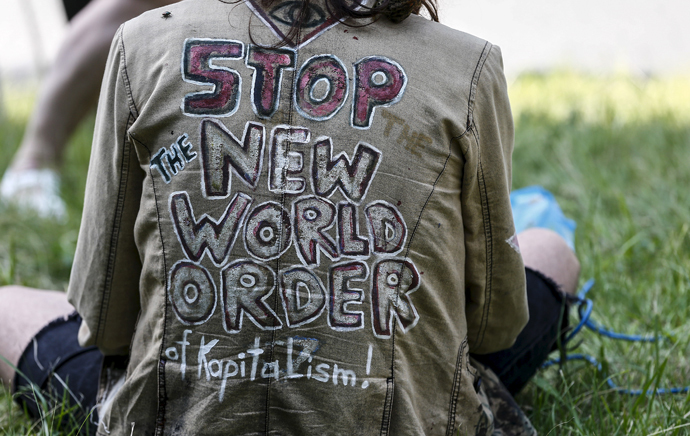 A protester sits on the ground next to a police check point prior to the Bilderberg meetings at Interalpen Hotel in the Austrian village of Buchen, June 11, 2015. (Reuters / Dominic Ebenbichler)