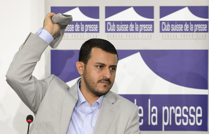 Head of Yemeni rebel's delegation Hamza al-Houthi throws back a shoe thrown at him by a representative of South Yemen during clashes at a press conference at the Geneva Press Club on June 18, 2015 in Geneva on Yemen peace talks. (AFP Photo / Fabrice Coffrini)