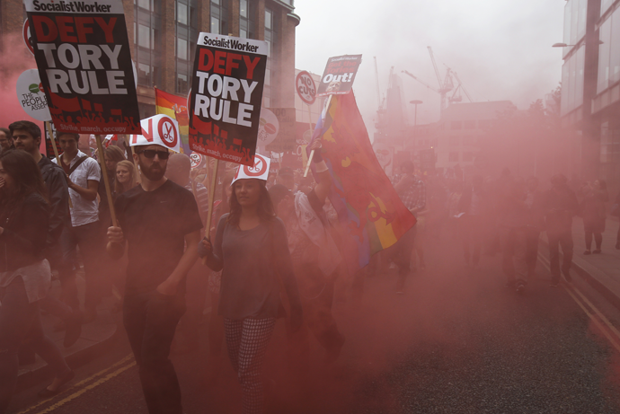 Demonstrators march through red smoke during an anti-austerity protest in central London, Britain June 20, 2015. (Reuters / Peter Nicholls)