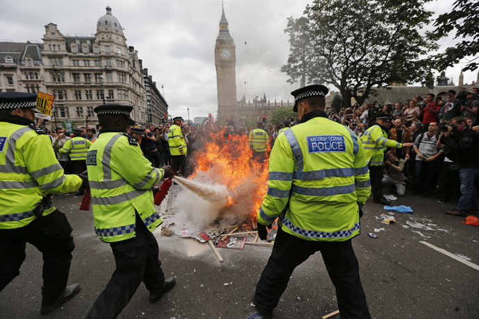 Police extinguish burning placards in front of parliament during an anti-austerity protest in central London, Britain June 20, 2015. (Reuters / Suzanne Plunkett)