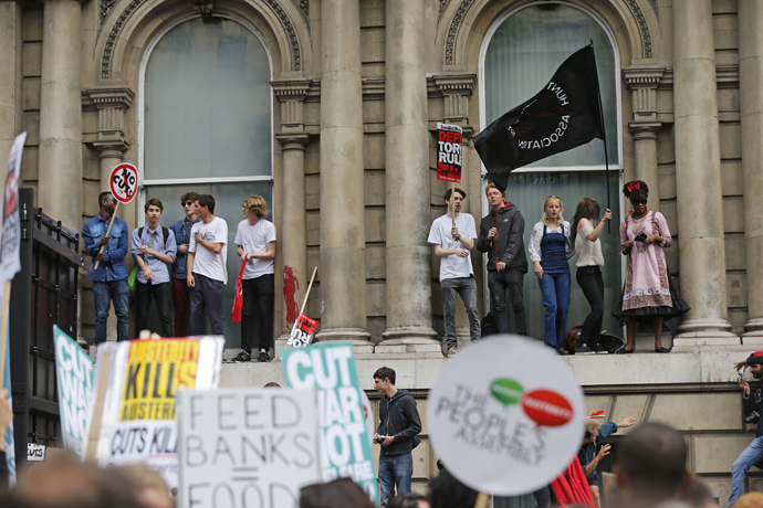 Demonstrators stand on a window ledge during an anti-austerity protest in central London, Britain June 20, 2015. (Reuters / Suzanne Plunkett)