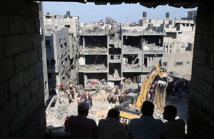 Palestinians watch as rescue workers search for victims under the rubble of a house, which witnesses said was destroyed in an Israeli air strike that killed three senior Hamas military commanders, in Rafah in the southern Gaza Strip August 21, 2014. (Reuters / Ibraheem Abu Mustafa)