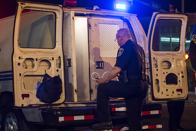 A policeman opens the back of a police van to load those detained for defying a curfew in west Baltimore, Maryland (Reuters / Adrees Latif)