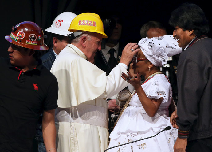 Pope Francis, wearing a helmet, blesses a woman as Bolivian President Evo Morales (R) looks on, during a World Meeting of Popular Movements in Santa Cruz, Bolivia, July 9, 2015. (Reuters/Alessandro Bianchi)