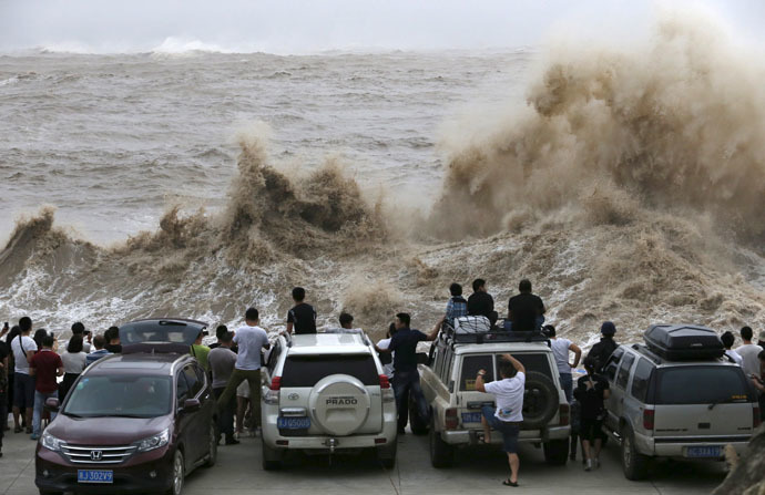 People look on as waves, under the influence of Typhoon Chan-hom, hit the shore in Wenling, Zhejiang province, China, July 10, 2015. (Reuters/William Hong)