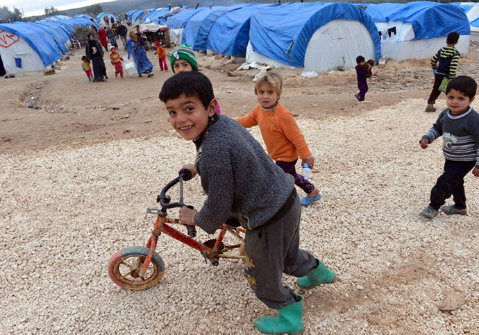 Syrian children play outside their tents at the refugee camp of Qah along the Turkish border in the village of Atme in the northwestern province of Idlib, on February 7, 2013. (AFP Photo / Aamir Qureshi)