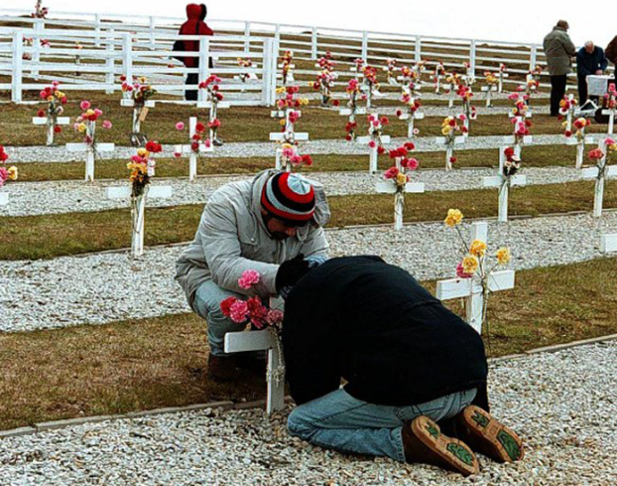 Relatives of Argentine soldiers who died during Argentina's 1982 war over the Falkland Islands decorate tombs at a cemetery. (AFP Photo / Angeline Montoya)