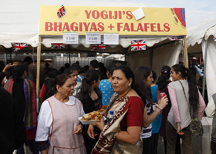 People walk past an Indian food stand at a street in northwest London. (Reuters / Suzanne Plunkett)