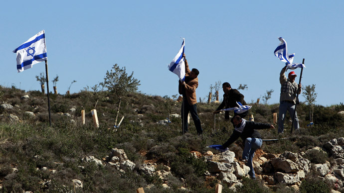Palestinian activists remove Israeli flags during a protest against what they say is Israel's denial of access to their farmland, in the village of Khirbet Zakaria, near the settlement bloc of Gush Etzion (Reuters/Ammar Awad)