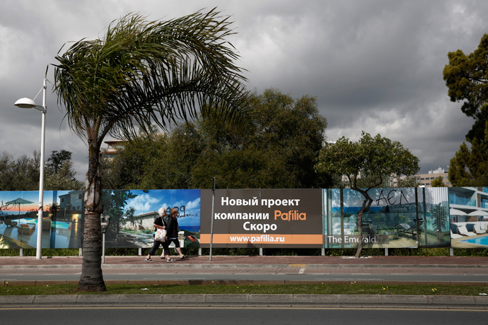 Two women make their way alongside Russian advertisements about a property development in Limassol, a coastal town in southern Cyprus (Reuters / Yorgos Karahalis) 