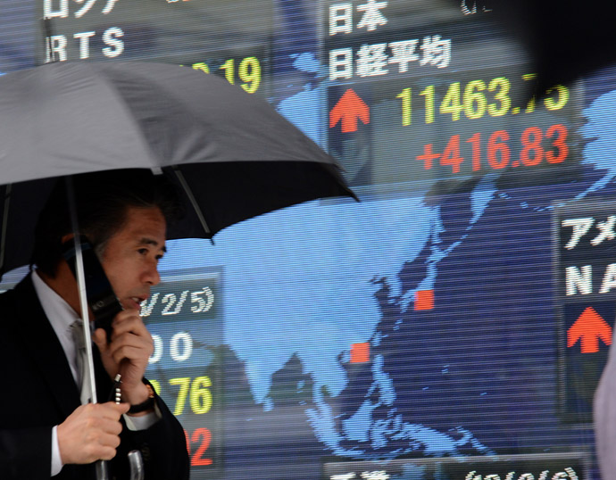A businessman walks in front of a digital share prices display board in Tokyo (AFP Photo)