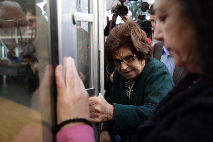 A woman holds the door of a Laiki bank branch in the Cypriot capital, Nicosia, on March 28, 2013, as people queue up outside waiting for the bank to open after an unprecedented 12-day lockdown (AFP Photo)