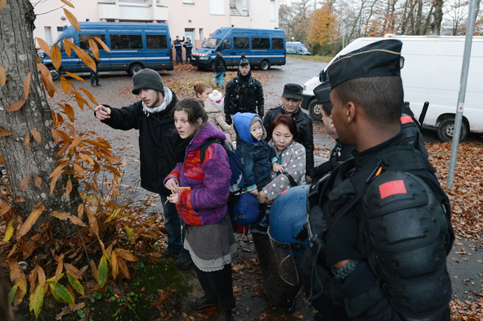 Migrants with children are escorted by gendarmes during the evacuation of a former retirement house in the early morning in Pace, western France. (AFP Photo)