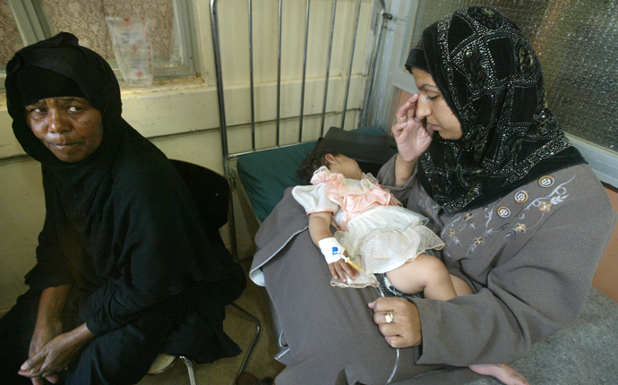 A woman sits in a ward of a hospital in Baghdad, 23 April 2003, holding her small girl ailing from gastroenteritis, in what local doctors believe is the beginning of an epidemic, mainly due to water contamination and rotting food mainly due to electricity blackouts (AFP Photo / Cris Bouroncle)