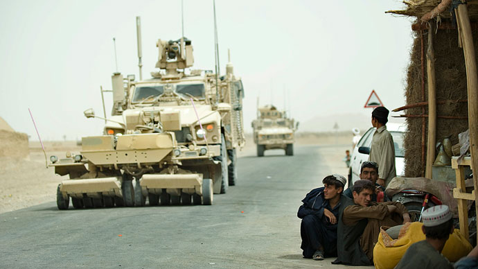 Afghani men gather near the road as a military convoy by soldiers from the 1st Platoon, 1-64 Armoured Batallion, US Army - operating under NATO - roll-past security patrols at Morghan-Kecha village in Daman district, Kandahar.(AFP Photo / Tony Karumba)
