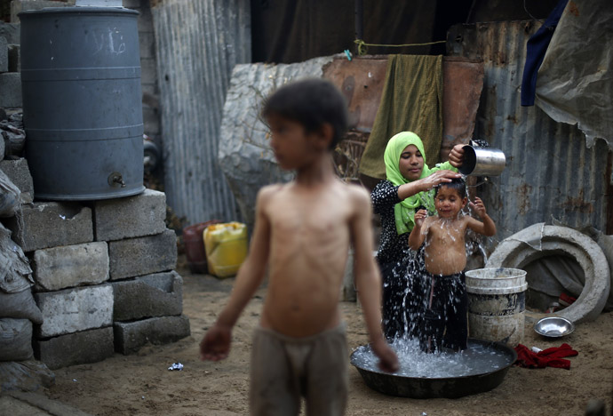 A Palestinian woman bathes her son near their dwelling on a hot day in Beit Lahiya, near the border between Israel and northern Gaza Strip April 7, 2013. (Reuters)