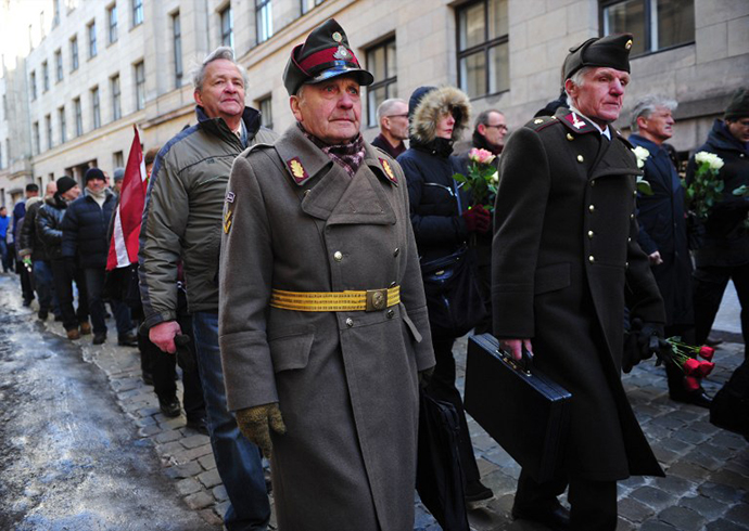 Two man dressed in pre-WWII Latvian military uniforms walk along with veterans of the Latvian Legion, a force that was commanded by the German Nazi Waffen SS, and their sympathizers to the Monument of Freedom in Riga, Latvia on March 16, 2013. (AFP Photo / Ilmars Znotins)
