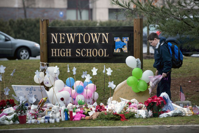 A student looks for a place to leave flowers at a makeshift memorial for the victims of the Sandy Hook Elementary School shooting at the entrance of Newtown High School December 18, 2012 in Newtown, Connecticut. (AFP Photo / Brendan Smialowski)