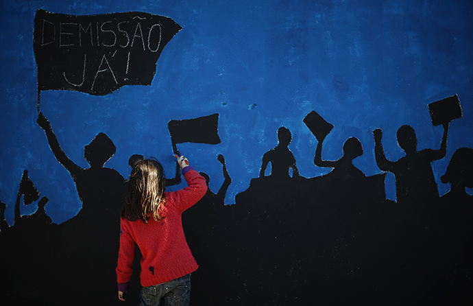 A member of "Damn the Troika" movement works on a mural in Lisbon February 24, 2013. (Reuters / Rafael Marchante)